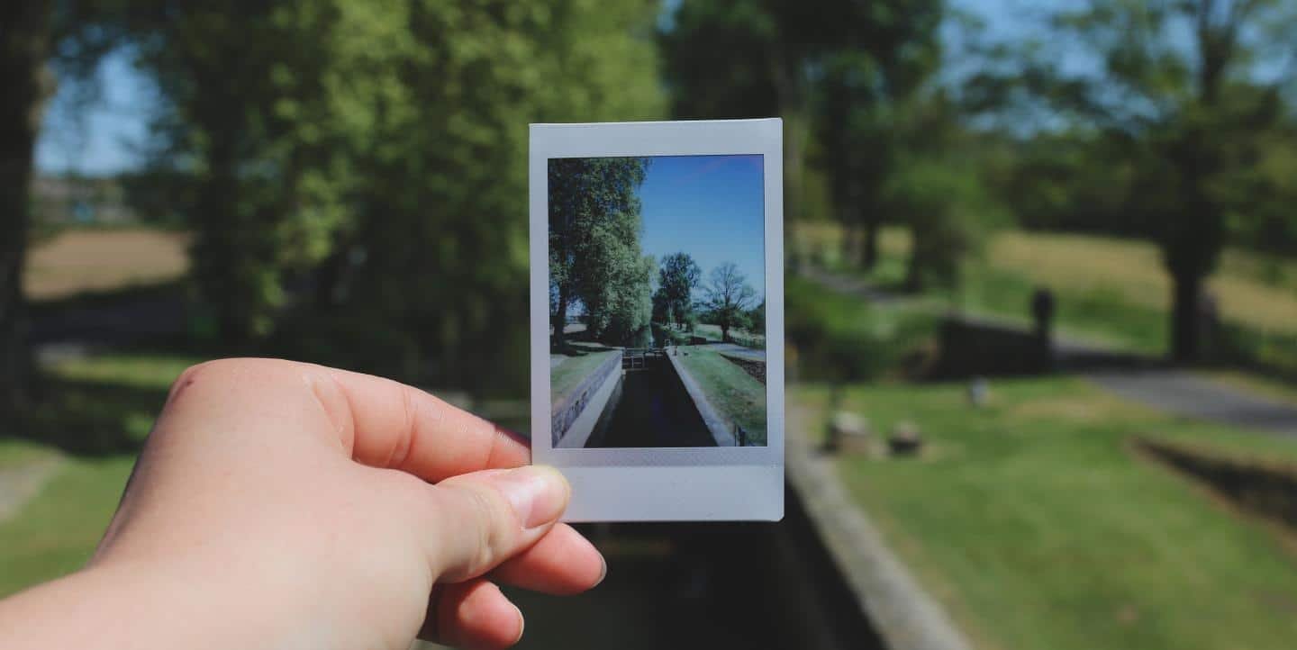 Decoration only: A photo of a person holding up a Polaroid picture of a street.
