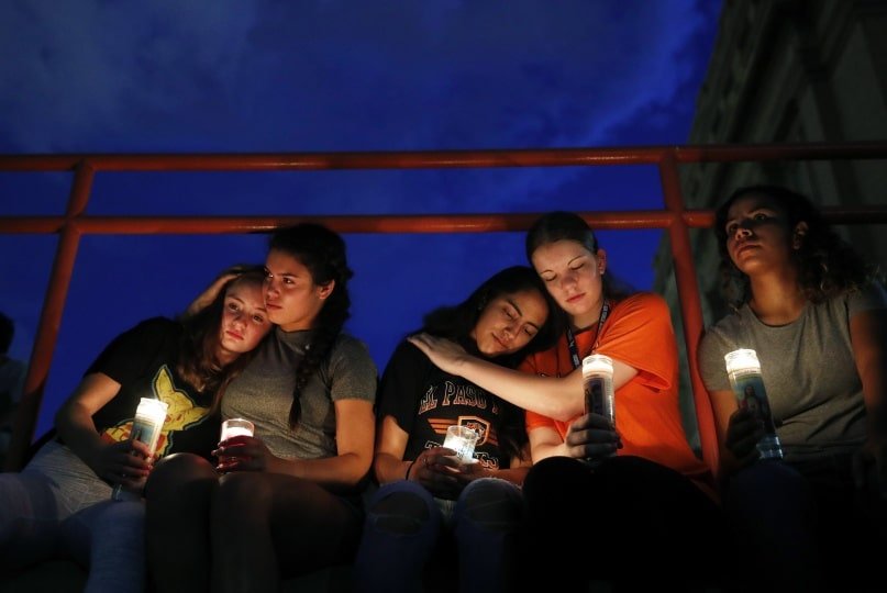 Decoration only: A photo of five people sitting and holding lit candles at a candlelight vigil in the wake of a mass shooting.