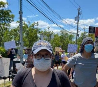 A woman wearing a mask marches in a protest.