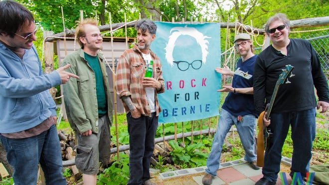 A group of men standing in front of a "Rock for Bernie" sign.