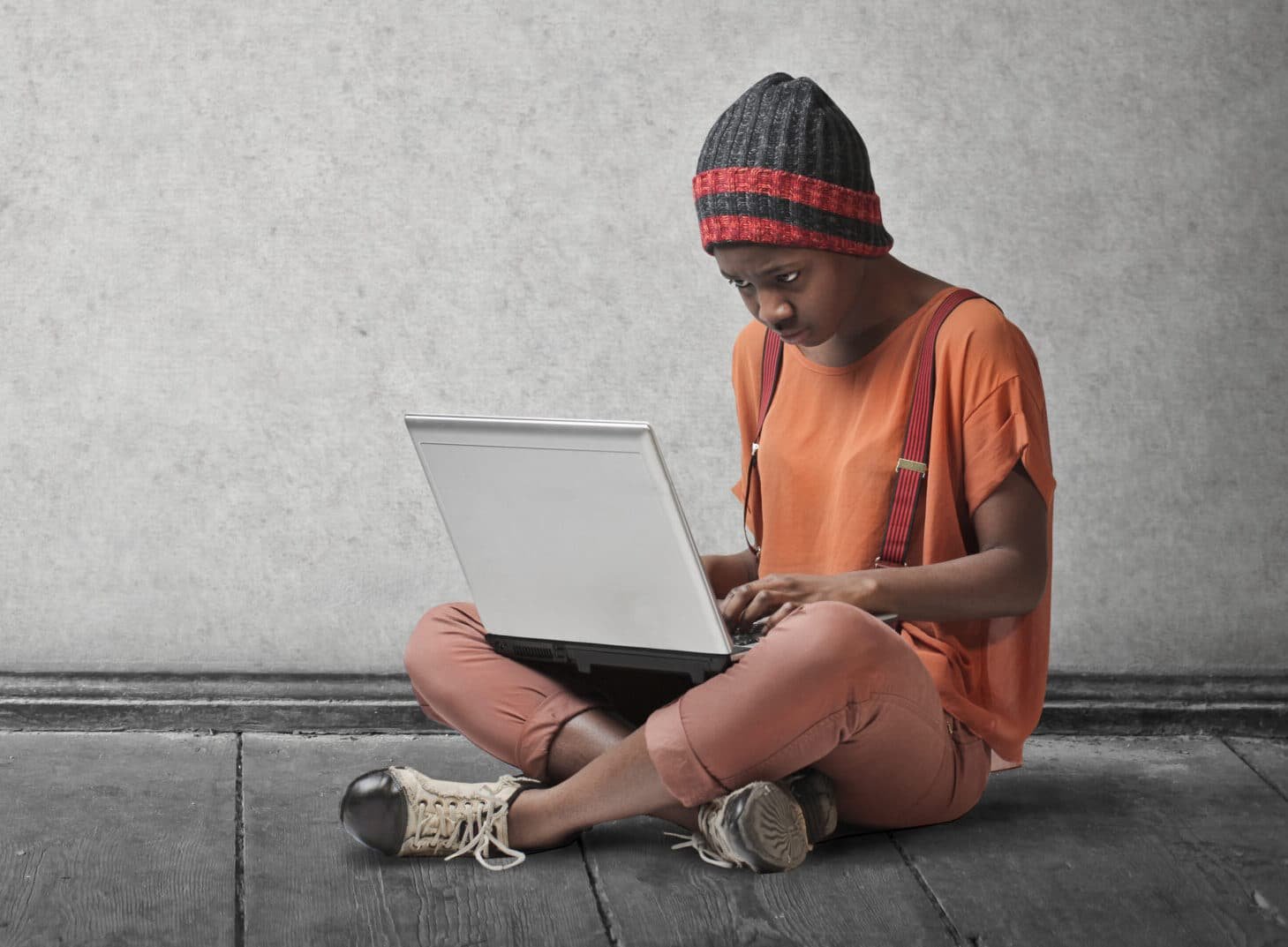 Girl wearing a beanie using a laptop.