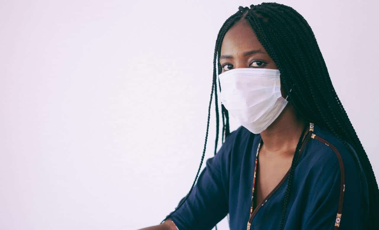 A black woman wearing a face mask stares at the camera.