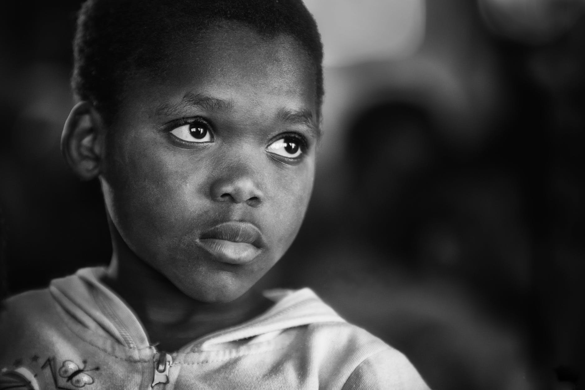 A Black child stares past the camera into the distance.